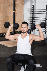 Man in sportswear working out with dumbbells in gym.