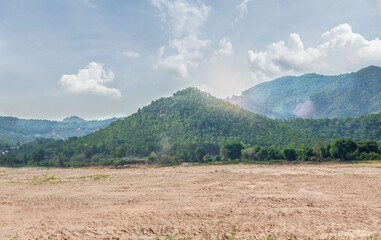 Fototapeta premium Empty dry cracked swamp reclamation soil, land plot for housing construction project with car tire print in rural area and beautiful blue sky with fresh air Land for sales landscape concept.