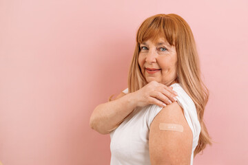 Vaccinated 50s 60s woman showing arm with plaster bandage after Covid-19 vaccine. Coronavirus...
