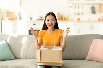 Online store, delivery service concept. Overjoyed asian lady unboxing carton parcel, emotional...