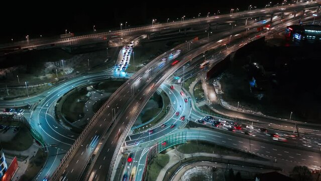 Aerial drone time lapse car traffic jam roundabout circle interchange road at night, top view junction highway intersection in evening. Timelapse cars driving busy junction crossroad fast motion
