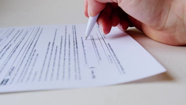 The woman signs the document. 4k close-up footage
