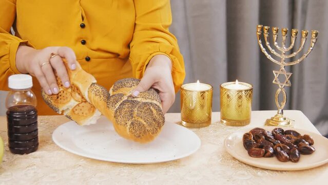 hands of a Jewish woman break the challah for a meal on Shabbat. Medium plan
