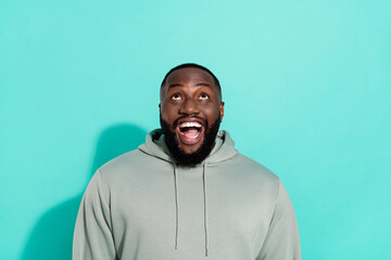 Portrait of attractive cheerful guy looking up guess copy space new isolated over bright teal...