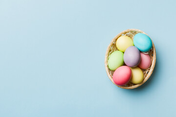 Multi colors Easter eggs in the woven basket on colored background . Pastel color Easter eggs. holiday concept with copy space