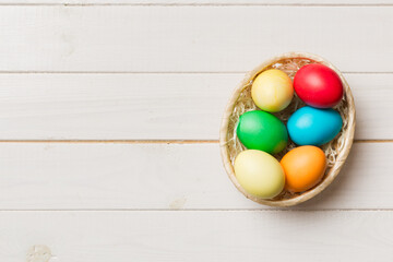 Multi colors Easter eggs in the woven basket on colored background . Pastel color Easter eggs. holiday concept with copy space