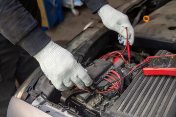 Selective focus an auto mechanic uses a multimeter voltmeter to check the voltage level in a car battery.