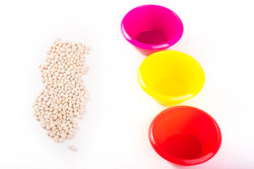 Fototapeta premium Developing lessons for young children. The development of fine motor skills. Haricot, beans and colored plastic bowl