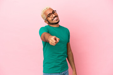 Young Colombian handsome man isolated on pink background pointing front with happy expression