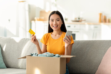 Online shopping and delivery service concept. Excited asian woman with credit card and smartphone,...