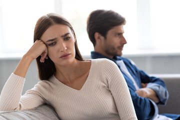 Portrait of offended sad european young woman ignores unhappy husband after quarrel in living room...