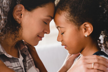Closeup portrait of african-american mother and small little young preteen daughter hugging embracing with eyes closed sharing love and care. Motherhood. Happy Mother`s day!