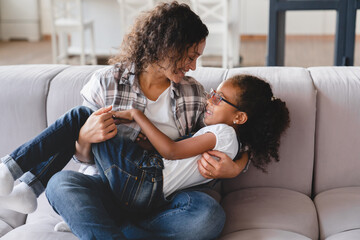 Childcare and nurturing. African mother holding little preteen girl daughter, spending time...