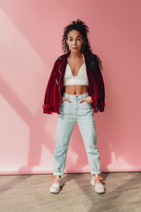 attractive black african american woman in stylish outfit on pink background