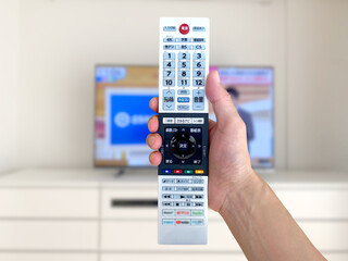 薄型テレビの前でリモコンをかざす手