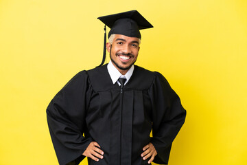 Young university graduate Colombian man isolated on yellow background posing with arms at hip and...
