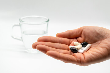 Pills on your palms and water in a transparent cup.