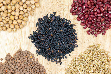 Five types of grain and beans on the wooden background.