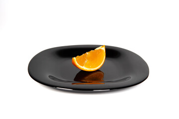 Black plate with orange slice and green apple on white background
