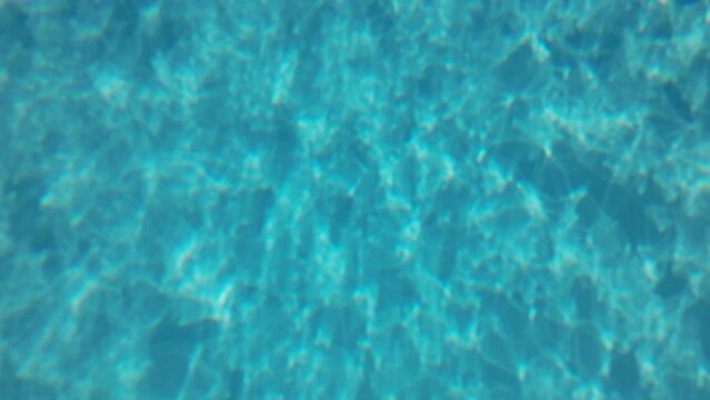 Underwater background, Slow motion of the glare of sunlight on the bottom of the pool. Natural blue background with sunbeams at the bottom of the pool