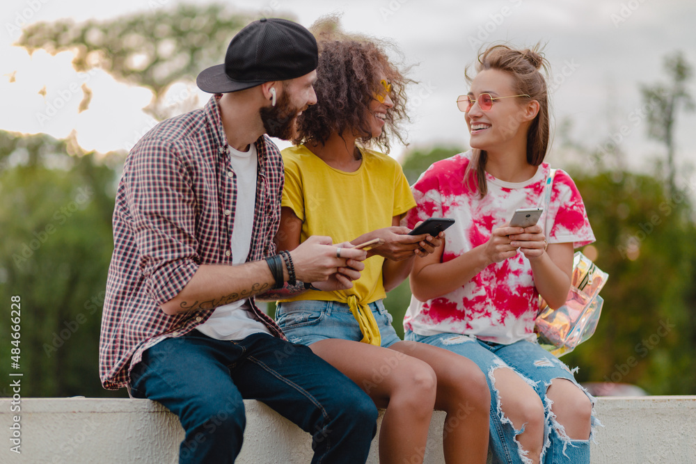 Wall mural happy young company of smiling friends sitting in park