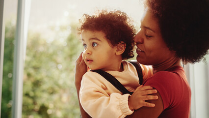 Loving Mother Hugging and Holding Adorable Baby Boy at Modern Home Living Room. Happy Mom Kissing...