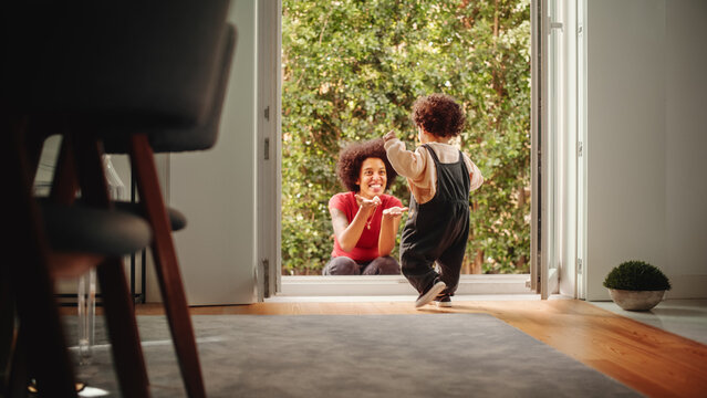 Happy Mother Playing with Adorable Baby Boy, Having Fun at Modern Home Living Room. Black Female Calling Toddler Child to Come Out to the Garden. Concept of Childhood, New Life, Parenthood.