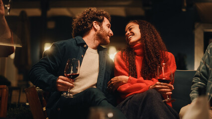 Loving Couple Sitting Together at a Garden Party Celebration with Friends on a Warm Summer Evening. Beautiful Man and Woman Enjoy Life on a Terrace, Talk, Relax on Weekend, Have Fun, Drink Wine.