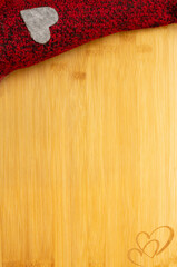 Bamboo wooden board with carved hearts and red cloth with a gray heart. Love valentine concept. Flat lay