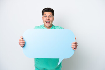 Young handsome caucasian man isolated on white bakcground holding an empty speech bubble with surprised expression