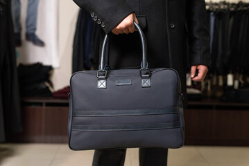 a man is holding a dark blue leather men's bag in his hand