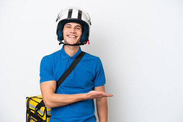 Young caucasian man with thermal backpack isolated on white background presenting an idea while looking smiling towards