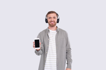 Man Listening to Music from Phone Showing Device. Man Holding Phone. Isolated
