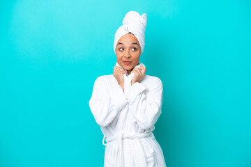 Young woman in a bathrobe with towel isolated on blue background - obrazy, fototapety, plakaty