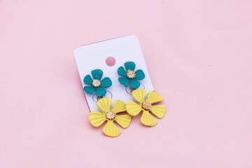 Flower design earrings on pink background.
