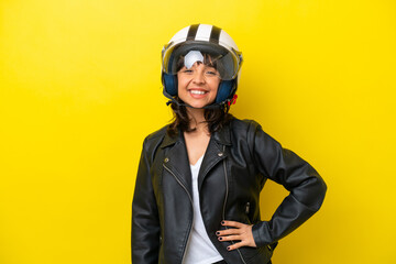 Young latin woman with a motorcycle helmet isolated on yellow background