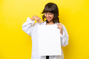 Young doctor latin woman isolated on yellow background holding an empty placard with happy...