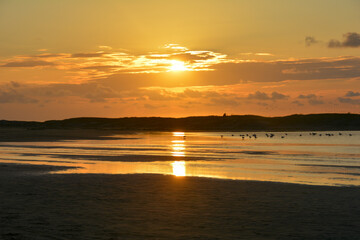 Sunset at low tide over the sea with sand beach