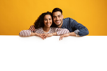 Happy Young Middle Eastern Couple Leaning At Big White Advertisement Board