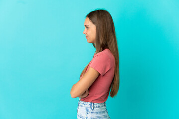 Young woman over isolated blue background in lateral position