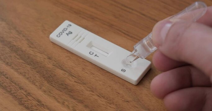 Liquid drops into cassette of Coronavirus Covid-19 at home rapid antigen self test, part of home testing procedure.