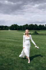 The bride runs barefoot on a green meadow. Summer day.