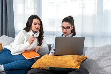 Two young women small business owners and partners interior designers working from home as freelancers making ideas for new design of homes for clients. Females thinking and consulting about work.