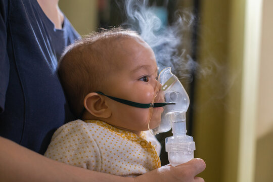 Closeup of baby inhaling fumes spray of the medication from a nebulizer