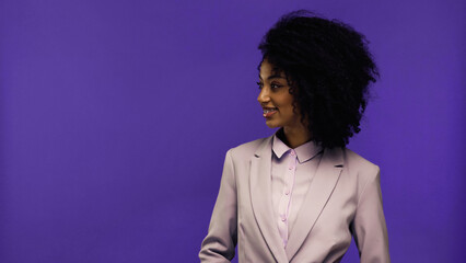 Fototapeta na wymiar cheerful african american businesswoman with braces looking away isolated on purple.