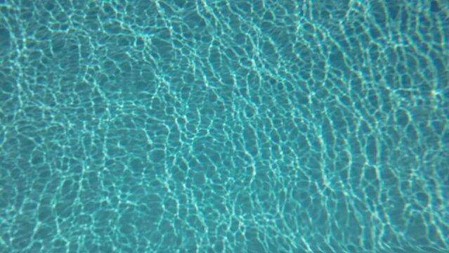 Underwater background, Slow motion glare of sunlight on the bottom of the pool. Natural blue background with sunbeams at the bottom of the pool