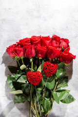Bouquet of red roses with two red hearts on gray concrete background. Copy space. Valentine's day concept.