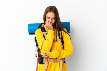 Young mountaineer woman with a big backpack over isolated white background having doubts