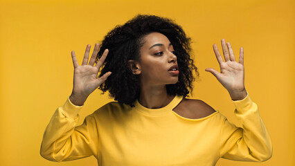 pretty young african american woman showing hands palms while performing mime acting isolated on...