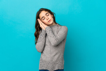 Little caucasian girl isolated on blue background making sleep gesture in dorable expression